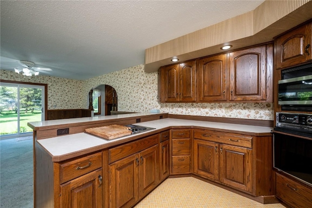 409 Oak St, Rowley, IA 52329 - kitchen featuring wallpapered walls, oven, arched walkways, cooktop, and a peninsula