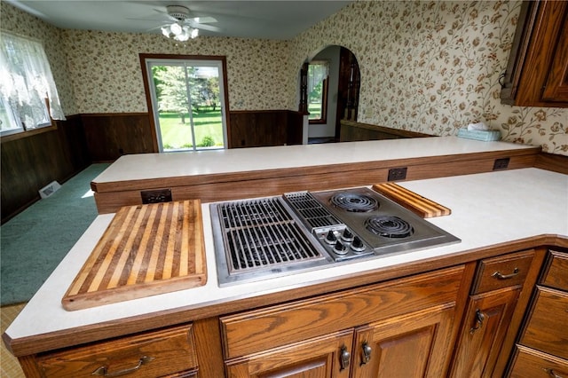 409 Oak St, Rowley, IA 52329 - kitchen with wallpapered walls, a wainscoted wall, light countertops, a ceiling fan, and brown cabinetry
