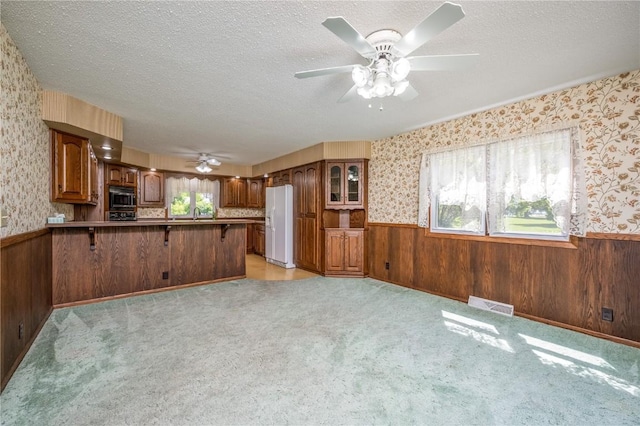 409 Oak St, Rowley, IA 52329 - kitchen with white fridge with ice dispenser, stainless steel microwave, wainscoting, wallpapered walls, and plenty of natural light