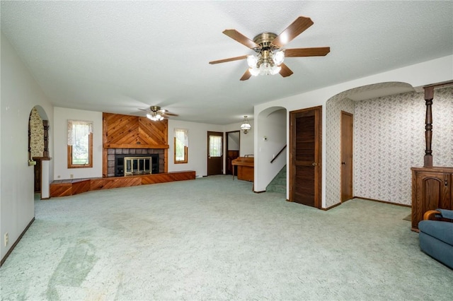 409 Oak St, Rowley, IA 52329 - unfurnished living room featuring arched walkways, a ceiling fan, carpet floors, baseboards, and a tiled fireplace