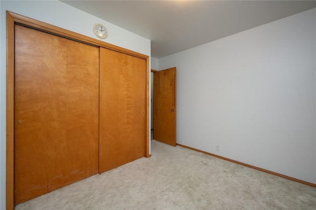 409 Oak St, Rowley, IA 52329 - unfurnished bedroom featuring a closet, light colored carpet, and baseboards