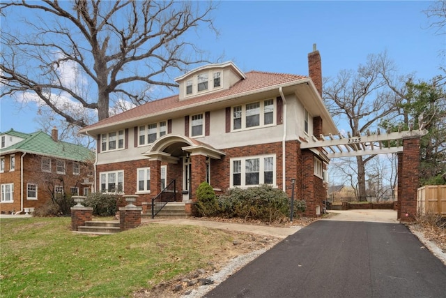 2325 Grande Ave SE, Cedar Rapids, IA 52403 - view of front of house featuring a chimney, a pergola, stucco siding, asphalt driveway, and brick siding