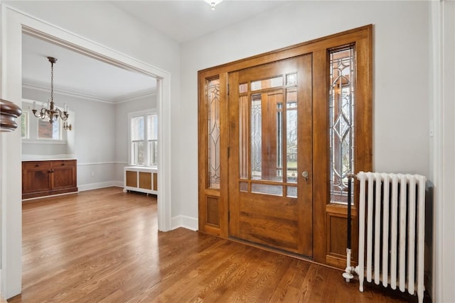 2325 Grande Ave SE, Cedar Rapids, IA 52403 - foyer with radiator heating unit, a chandelier, wood finished floors, baseboards, and ornamental molding