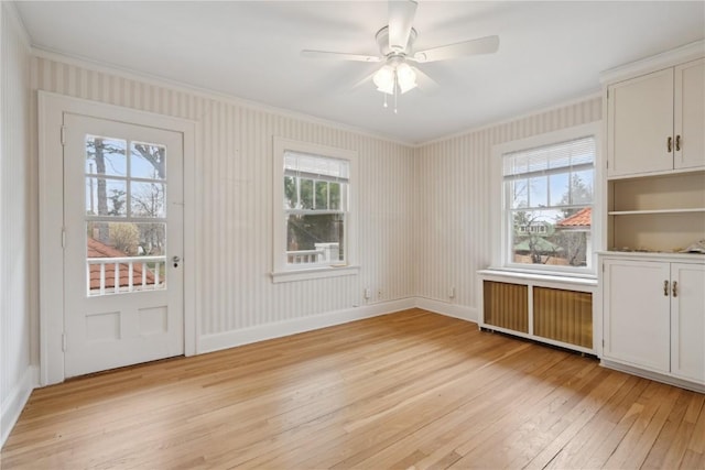 2325 Grande Ave SE, Cedar Rapids, IA 52403 - unfurnished dining area featuring radiator heating unit, ornamental molding, light wood-type flooring, plenty of natural light, and a ceiling fan