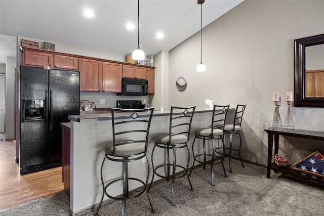 302 Duchess Dr, Solon, IA 52333 - kitchen with black appliances, a breakfast bar area, a peninsula, hanging light fixtures, and dark countertops