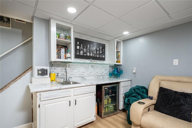 4721 Midway Dr NW, Cedar Rapids, IA 52405 - indoor wet bar featuring wine cooler, backsplash, light wood-type flooring, and a paneled ceiling
