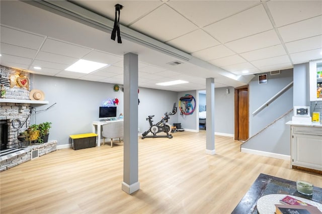 4721 Midway Dr NW, Cedar Rapids, IA 52405 - exercise room with a paneled ceiling, light wood-type flooring, and a brick fireplace