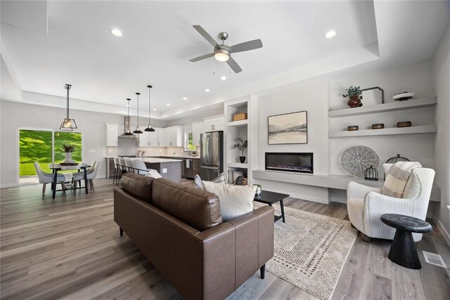 706 Silver Ln, Iowa City, IA 52245 - living room featuring a tray ceiling, a ceiling fan, light wood-style floors, recessed lighting, and built in shelves