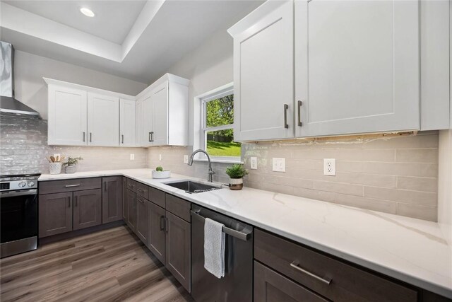 706 Silver Ln, Iowa City, IA 52245 - kitchen featuring stainless steel appliances, a sink, wall chimney range hood, white cabinets, and wood finished floors