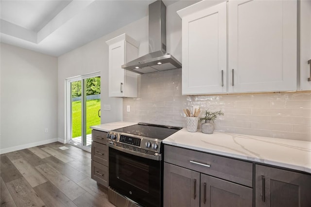 706 Silver Ln, Iowa City, IA 52245 - kitchen with wall chimney exhaust hood, stainless steel electric stove, dark wood finished floors, baseboards, and white cabinets
