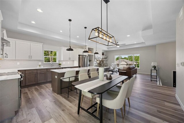 706 Silver Ln, Iowa City, IA 52245 - dining room with a tray ceiling, light wood-style flooring, recessed lighting, baseboards, and a chandelier
