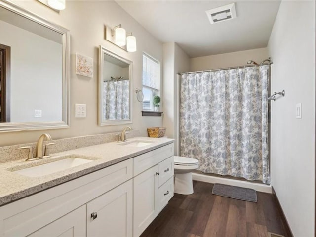 902 Creekside Dr, Tiffin, IA 52340 - bathroom featuring wood finished floors, toilet, double vanity, and a shower with curtain