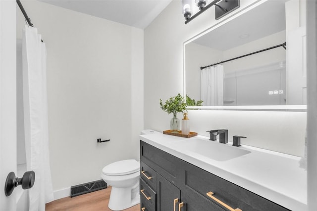 1418 26th St NW, Cedar Rapids, IA 52405 - bathroom featuring vanity, toilet, wood finished floors, baseboards, and a shower with shower curtain