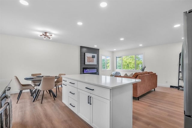 1418 26th St NW, Cedar Rapids, IA 52405 - kitchen featuring open floor plan, a large fireplace, recessed lighting, white cabinets, and light wood-style flooring