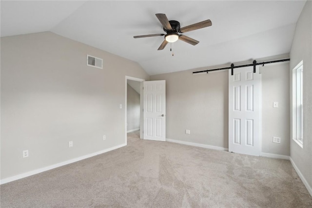 306 7th Ave, Clarence, IA 52216 - unfurnished bedroom with lofted ceiling, carpet flooring, a barn door, multiple windows, and baseboards