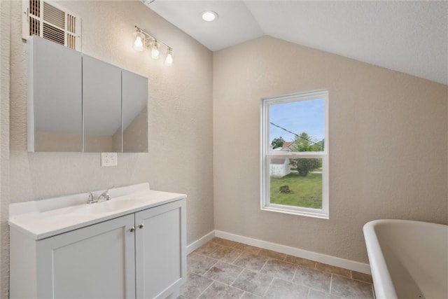 306 7th Ave, Clarence, IA 52216 - bathroom featuring a soaking tub, vanity, vaulted ceiling, and baseboards