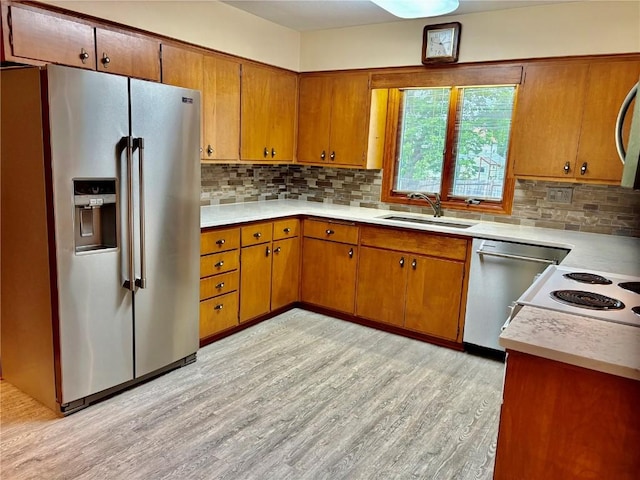 832 17th St SE, Cedar Rapids, IA 52403 - kitchen with appliances with stainless steel finishes, a sink, brown cabinetry, and light wood-style floors