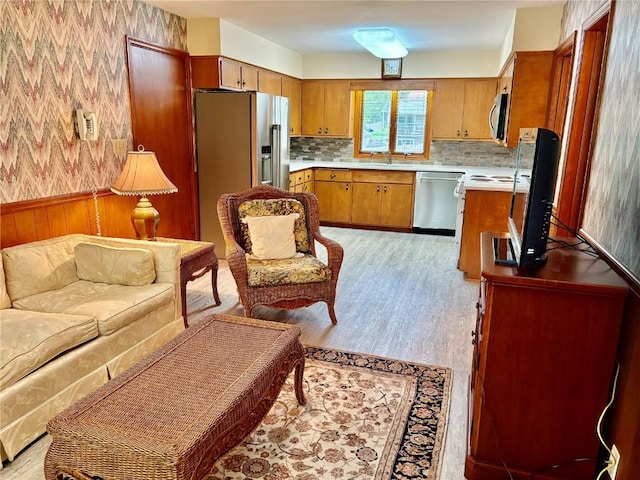 832 17th St SE, Cedar Rapids, IA 52403 - kitchen with stainless steel appliances, brown cabinetry, wallpapered walls, light countertops, and open floor plan