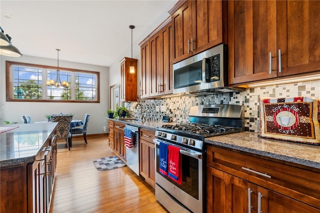 1617 Hunters Field Ln, Marion, IA 52302 - kitchen featuring appliances with stainless steel finishes, decorative backsplash, light wood finished floors, a chandelier, and pendant lighting