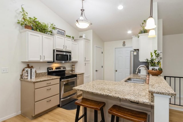 2806 Dawn Ave SW, Cedar Rapids, IA 52404 - kitchen with appliances with stainless steel finishes, a kitchen bar, light wood finished floors, lofted ceiling, and recessed lighting