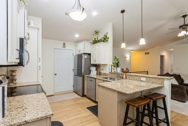 2806 Dawn Ave SW, Cedar Rapids, IA 52404 - kitchen featuring appliances with stainless steel finishes, a peninsula, open floor plan, light wood-style flooring, and vaulted ceiling
