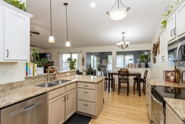 2806 Dawn Ave SW, Cedar Rapids, IA 52404 - kitchen with appliances with stainless steel finishes, lofted ceiling, a peninsula, light wood-type flooring, and decorative light fixtures