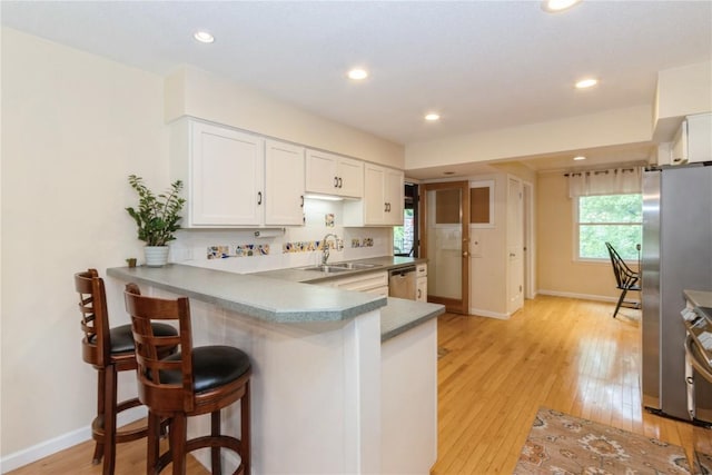2232 Birchwood Dr NE, Cedar Rapids, IA 52402 - kitchen with appliances with stainless steel finishes, a sink, light wood-style floors, white cabinets, and a kitchen breakfast bar