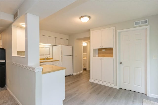 2232 Birchwood Dr NE, Cedar Rapids, IA 52402 - kitchen with freestanding refrigerator, white cabinets, light wood-type flooring, baseboards, and a sink