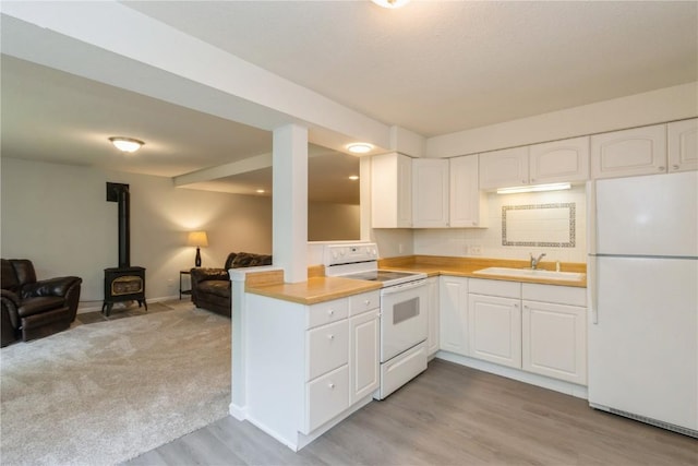 2232 Birchwood Dr NE, Cedar Rapids, IA 52402 - kitchen with white appliances, a sink, a wood stove, open floor plan, and light countertops
