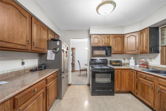 2623 Iris Ave NW, Cedar Rapids, IA 52405 - kitchen with black appliances, brown cabinetry, light flooring, a textured ceiling, and a sink