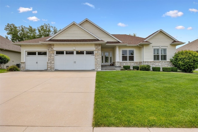 3355 Wild Rose Rd, Cedar Rapids, IA 52411 - view of front of home with stone siding, concrete driveway, a garage, and a front yard