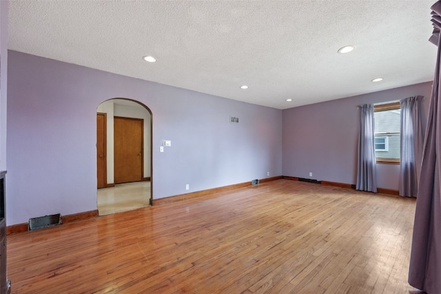 307 2nd Ave, Clarence, IA 52216 - spare room with arched walkways, light wood-type flooring, a textured ceiling, recessed lighting, and baseboards
