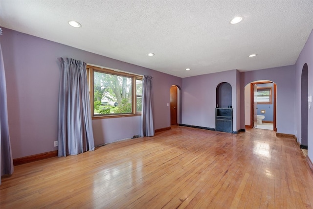 307 2nd Ave, Clarence, IA 52216 - empty room featuring arched walkways, a textured ceiling, light wood-type flooring, recessed lighting, and baseboards