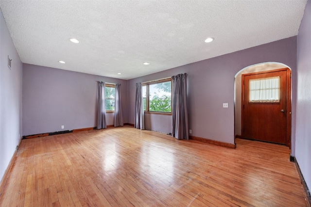 307 2nd Ave, Clarence, IA 52216 - empty room featuring arched walkways, light wood-style floors, a textured ceiling, recessed lighting, and baseboards