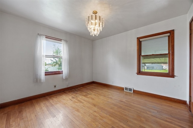 307 2nd Ave, Clarence, IA 52216 - spare room featuring a chandelier, light wood-type flooring, and baseboards