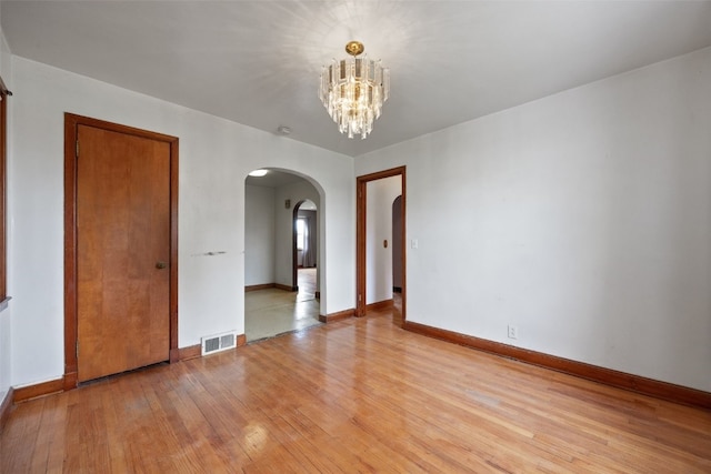 307 2nd Ave, Clarence, IA 52216 - empty room featuring arched walkways, light wood finished floors, a chandelier, and baseboards