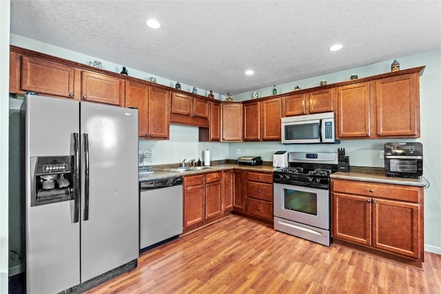 3107 Johnson Ave NW Unit 4, Cedar Rapids, IA 52405 - kitchen featuring appliances with stainless steel finishes, light wood-type flooring, a textured ceiling, brown cabinetry, and recessed lighting