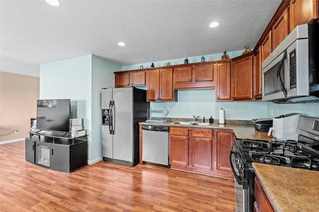 3107 Johnson Ave NW Unit 4, Cedar Rapids, IA 52405 - kitchen featuring stainless steel appliances, a sink, light wood-style flooring, a textured ceiling, and brown cabinetry