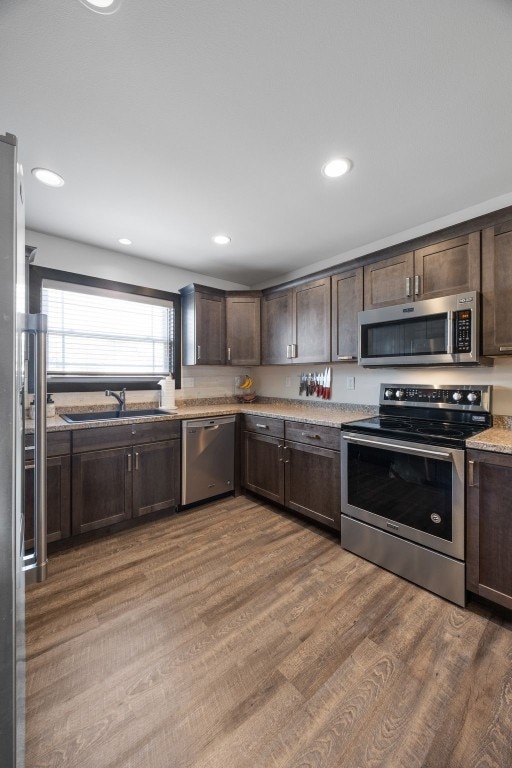 2205 Snapdragon Cir SW, Cedar Rapids, IA 52404 - kitchen with appliances with stainless steel finishes, dark brown cabinets, a sink, wood finished floors, and recessed lighting