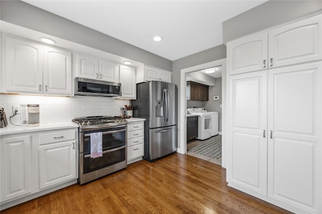 1355 Red Star Rd, Tipton, IA 52772 - kitchen featuring stainless steel appliances, washer and clothes dryer, wood finished floors, white cabinets, and light countertops