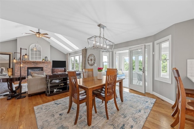 1355 Red Star Rd, Tipton, IA 52772 - dining space featuring a fireplace, light wood finished floors, lofted ceiling, ceiling fan, and baseboards