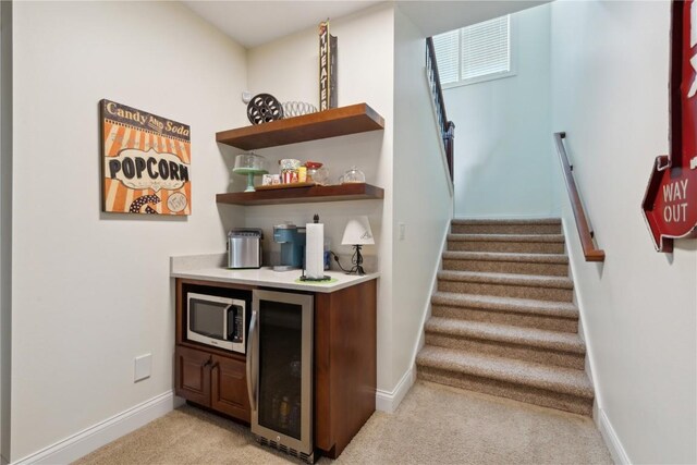 1485 Huntington Hills Dr, Marion, IA 52302 - indoor dry bar with wine cooler, light colored carpet, baseboards, stainless steel microwave, and stairs