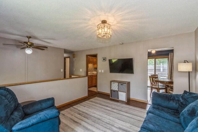 5817 Underwood SW, Cedar Rapids, IA 52404 - living room with light wood finished floors, a chandelier, baseboards, and a textured ceiling