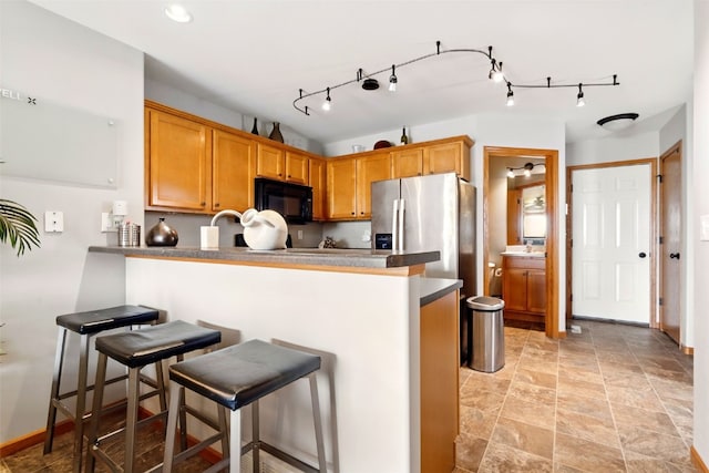 2900 Samuel Ct SW Unit D, Cedar Rapids, IA 52404 - kitchen featuring black microwave, a peninsula, a breakfast bar, light stone finish floors, and brown cabinetry