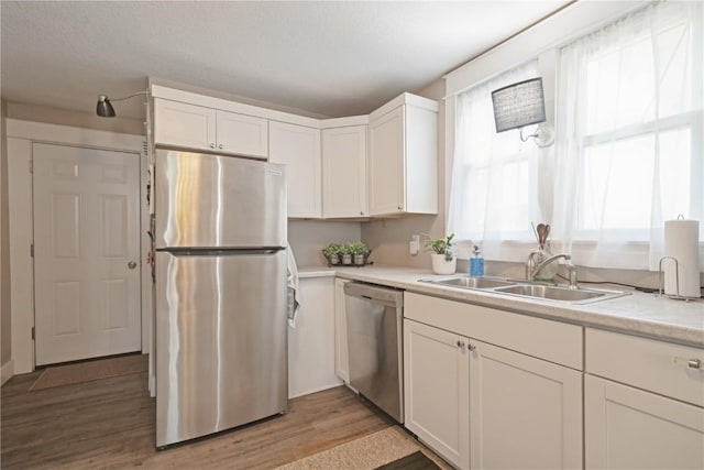 407 7th Ave SW, Cedar Rapids, IA 52404 - kitchen featuring stainless steel appliances, a sink, light wood finished floors, white cabinetry, and light countertops