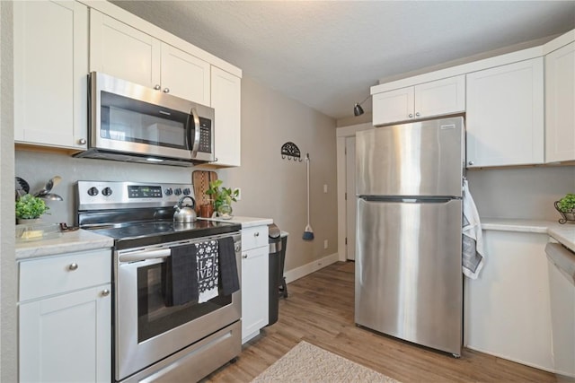 407 7th Ave SW, Cedar Rapids, IA 52404 - kitchen featuring appliances with stainless steel finishes, light wood-style floors, light countertops, and white cabinets