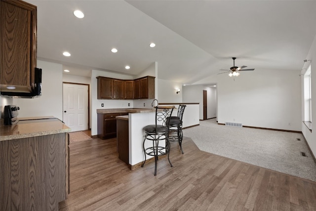 4565 Meadow Creek Dr, Palo, IA 52324 - kitchen featuring stove, a peninsula, a ceiling fan, vaulted ceiling, and a breakfast bar area