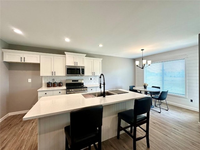 914 Juneberry Dr, Palo, IA 52324 - kitchen featuring stainless steel appliances, baseboards, a sink, light wood finished floors, and decorative backsplash