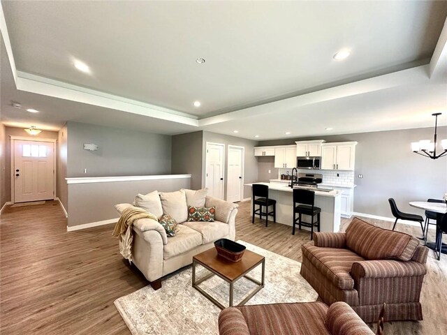 914 Juneberry Dr, Palo, IA 52324 - living room with a raised ceiling, light wood-style floors, baseboards, a chandelier, and recessed lighting