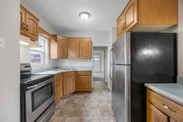 1814 9th St SW, Cedar Rapids, IA 52404 - kitchen featuring appliances with stainless steel finishes, under cabinet range hood, a sink, light countertops, and stone finish flooring